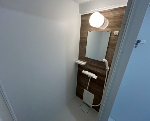 大田区の賃貸マンション原状回復工事でリニューアルした独立シャワールーム。木目調アクセントパネルとLED照明でホテルライクに仕上げた浴室」