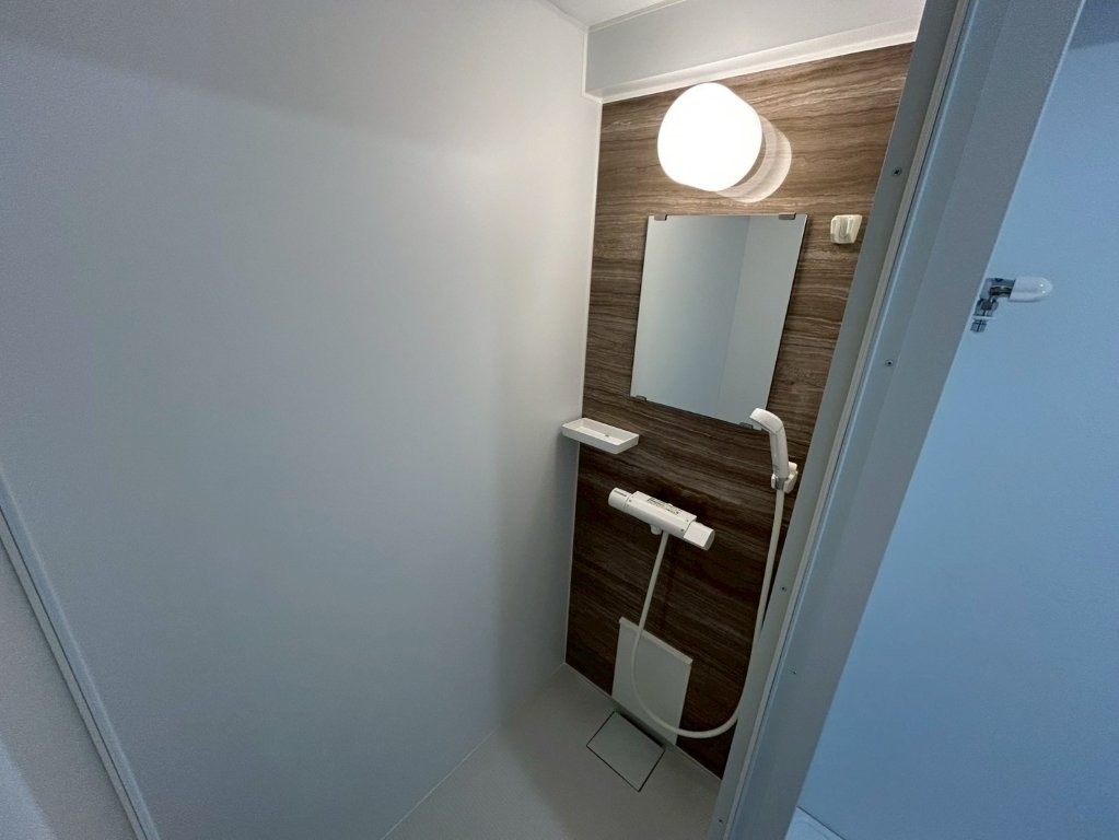 大田区の賃貸マンション原状回復工事でリニューアルした独立シャワールーム。木目調アクセントパネルとLED照明でホテルライクに仕上げた浴室」