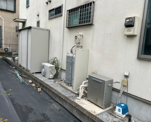 埼玉県久喜市の戸建て住宅で、エコキュートを撤去しLPガス給湯器(24号据置型)を新設した施工後の様子。ガスボンベと給湯器が整然と設置され、安全な配管工事が完了している。