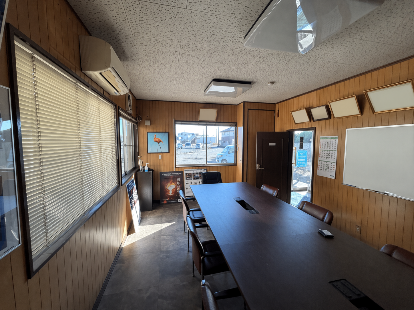 茨城県古河市の会社事務所におけるクロス張替え前の会議室 木目調壁面で暗い印象の施工前状態